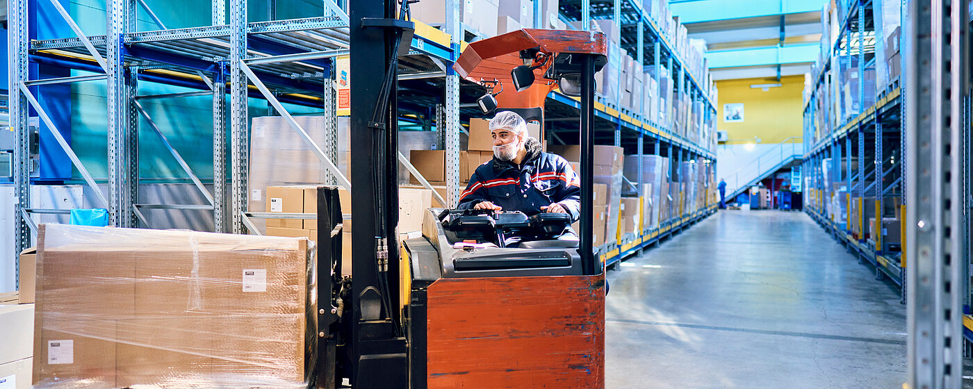 Mitarbeiter auf einem Gabelstapler im Hochregallager.