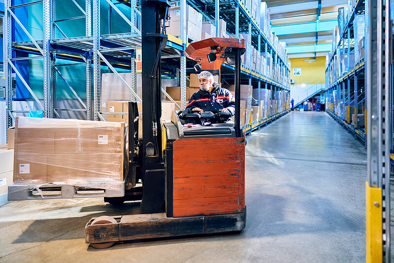 Mitarbeiter auf einem Gabelstapler im Hochregallager.