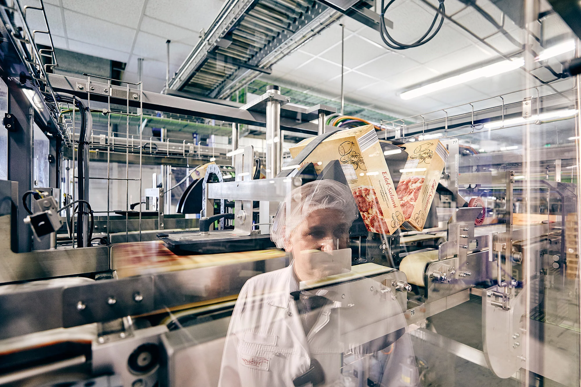 Mitarbeiterin in Arbeitskleidung in einer Produktionshalle.