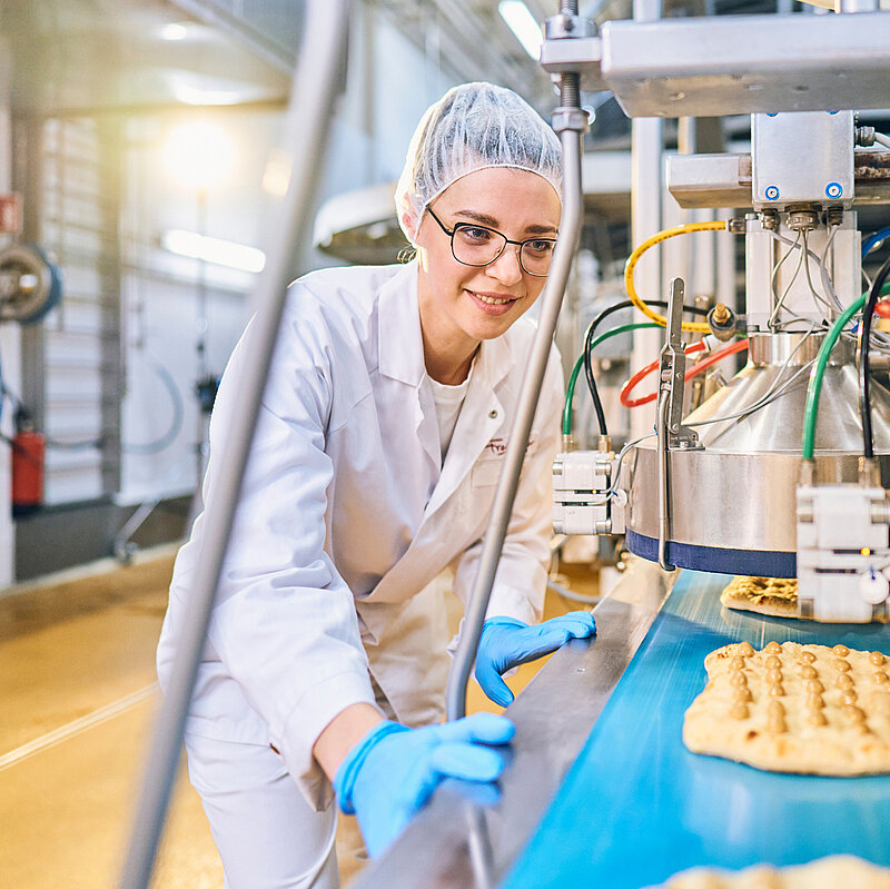 Mitarbeitende in der Produktion beim Schritt des Pizzateigs.