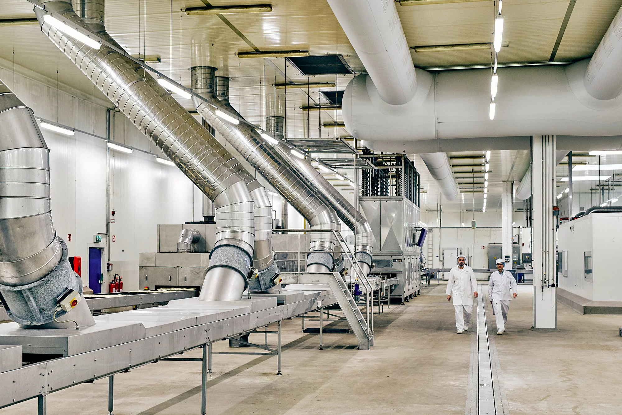 Zwei Mitarbeiter laufen durch eine Produktionshalle.