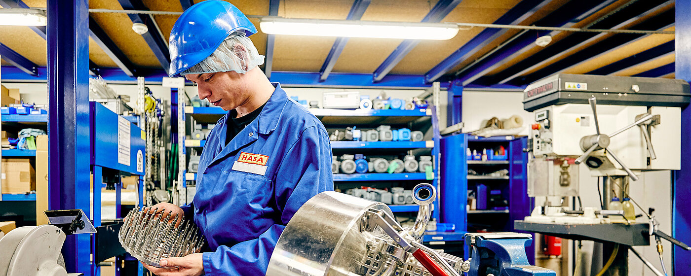 Mitarbeiter in Arbeitskleidung schraubend an einer Maschine.