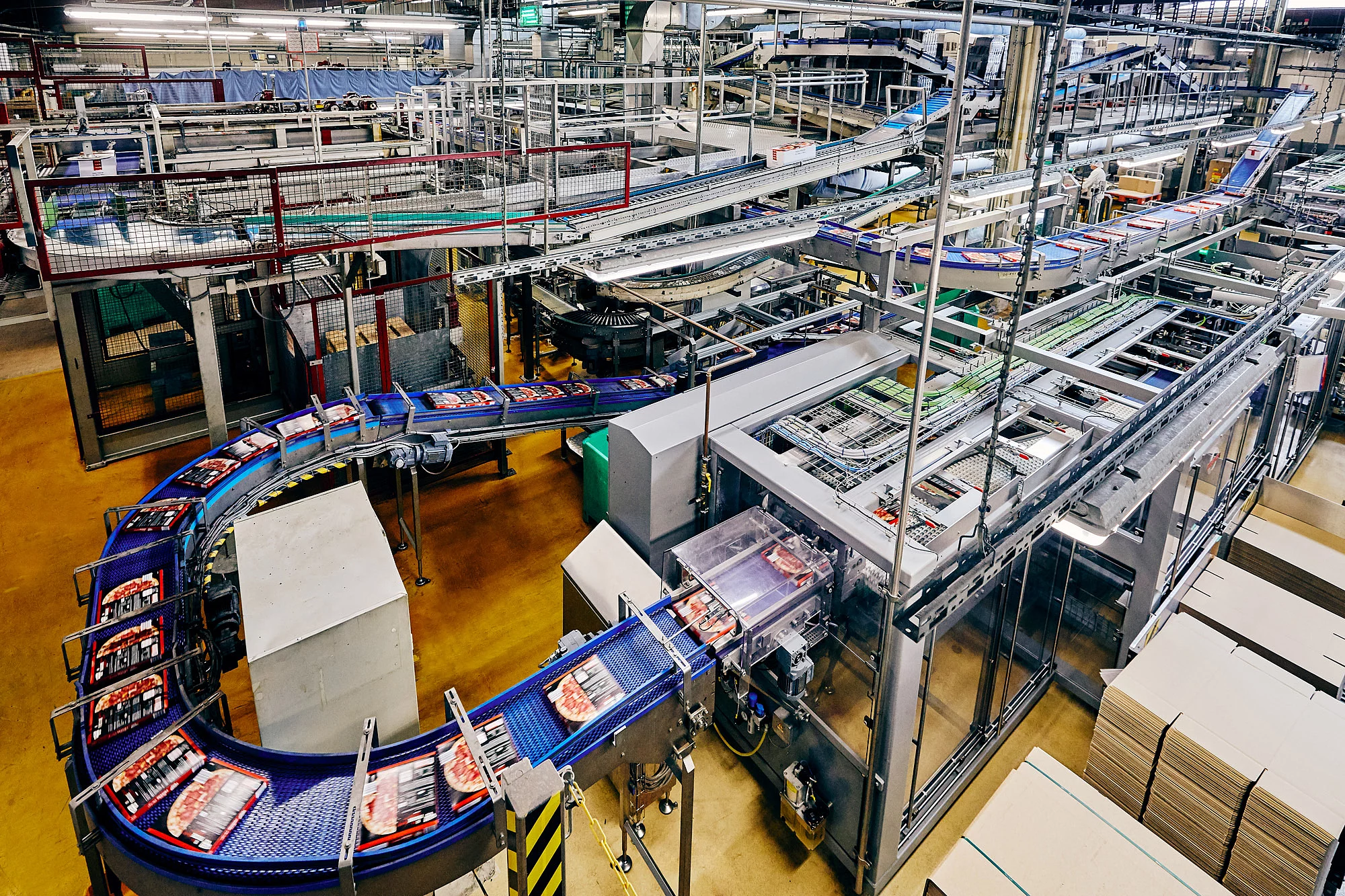 Vogelperspektive einer Maschine in einer Produktion, bestückt mit Pizzakartons.