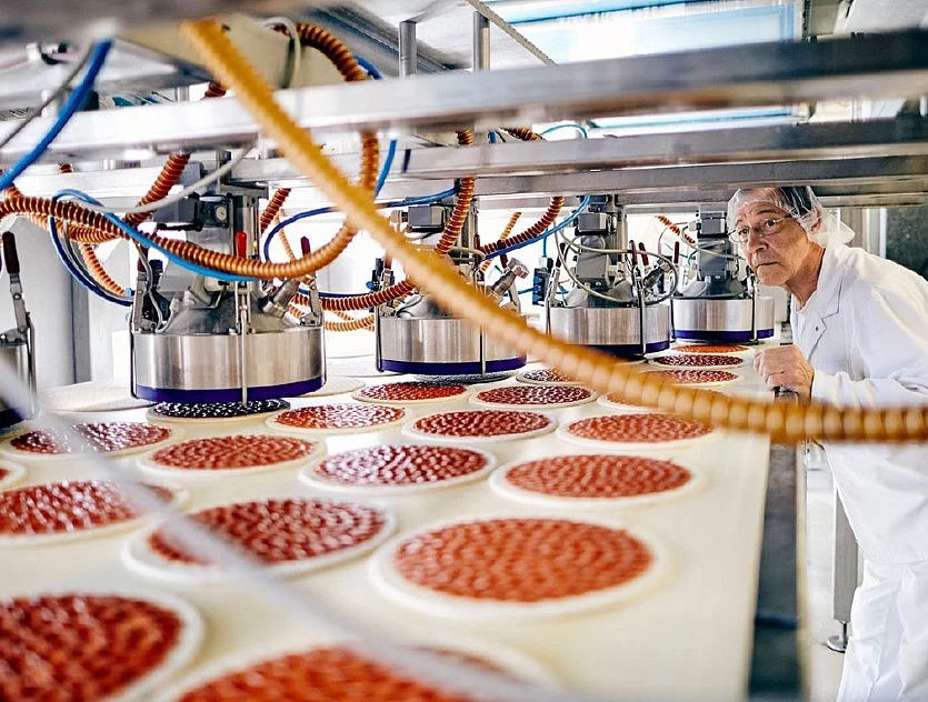 Mitarbeiter in Arbeitskleidung an Produktionsmaschine.