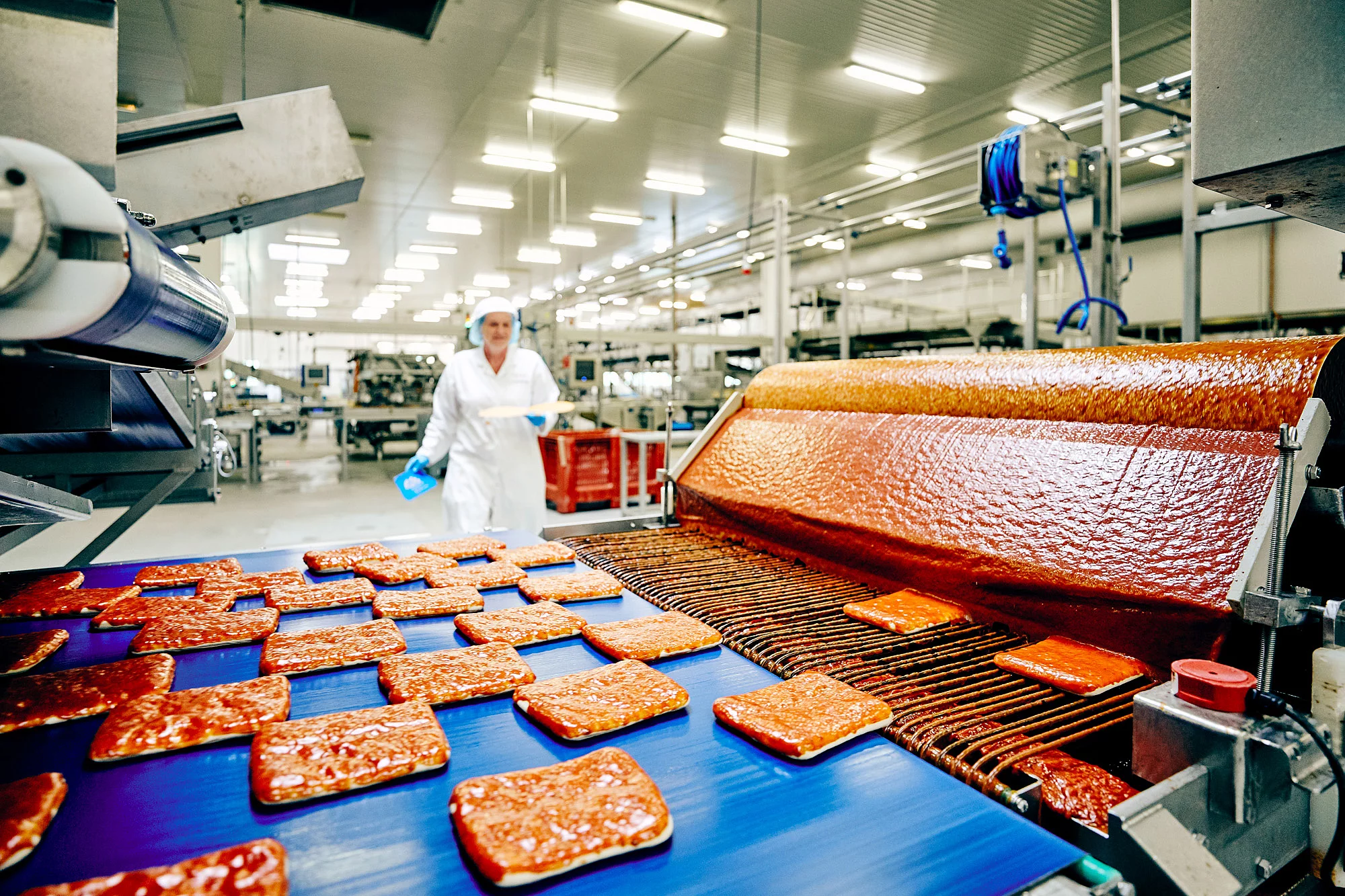 Eine Maschine in der Lebensmittelproduktion und eine Mitarbeiterin im Hintergrund.