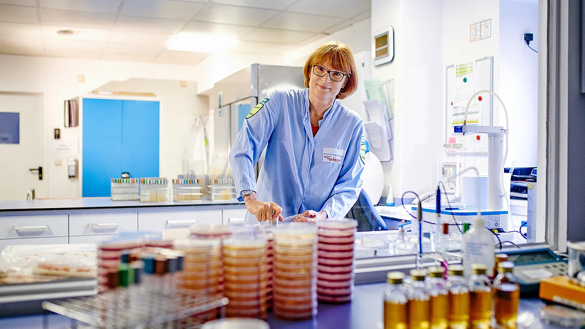 Mitarbeiterin in Arbeitskleidung in der Produktion am Abfüllen.