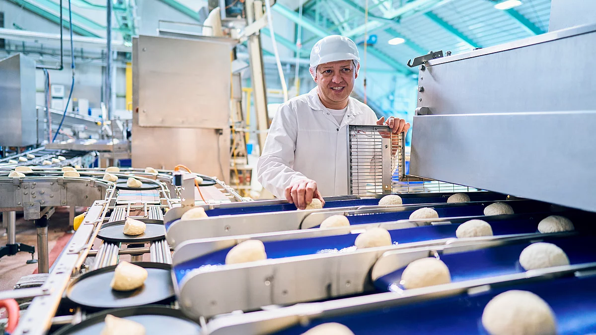 Mitarbeiter in Arbeitskleidung an Produktionsband.