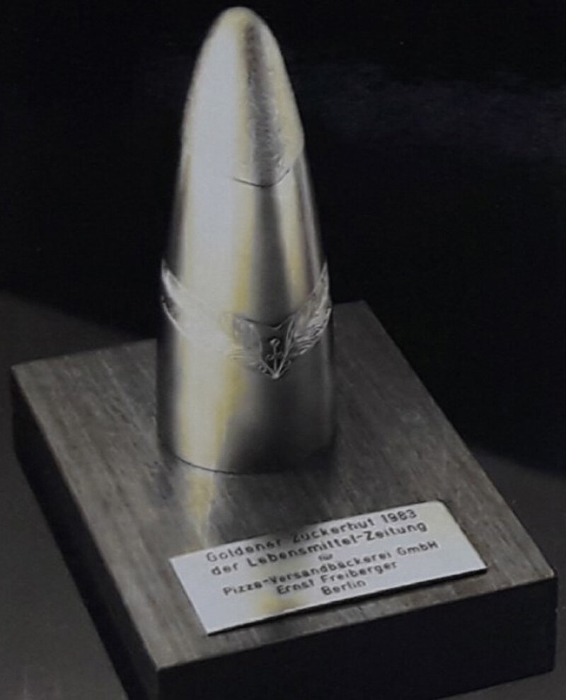 Goldener Zuckerhut auf einer Holzplatte. Preis von 1983 der Lebensmittel-Zeitung.