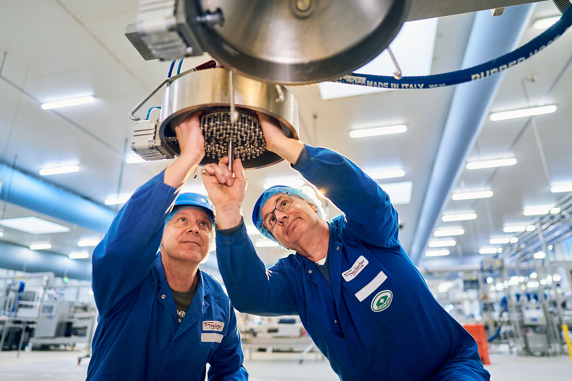 Zwei Mitarbeiter schauen in eine Maschine und schrauben darin. 