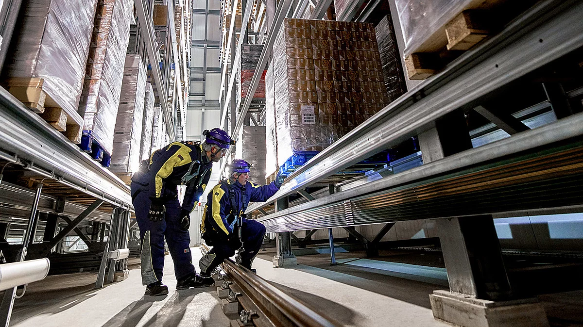 Zwei Mitarbeitende in Arbeitskleidung am Hochregallager.