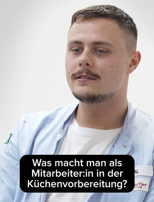 Eine sitzende Person in Alltagskleidung.