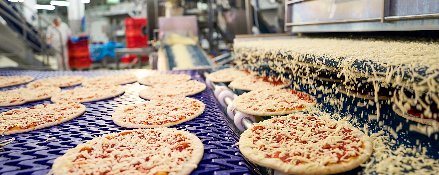 Pizzen in der Produktion auf dem Fließband.