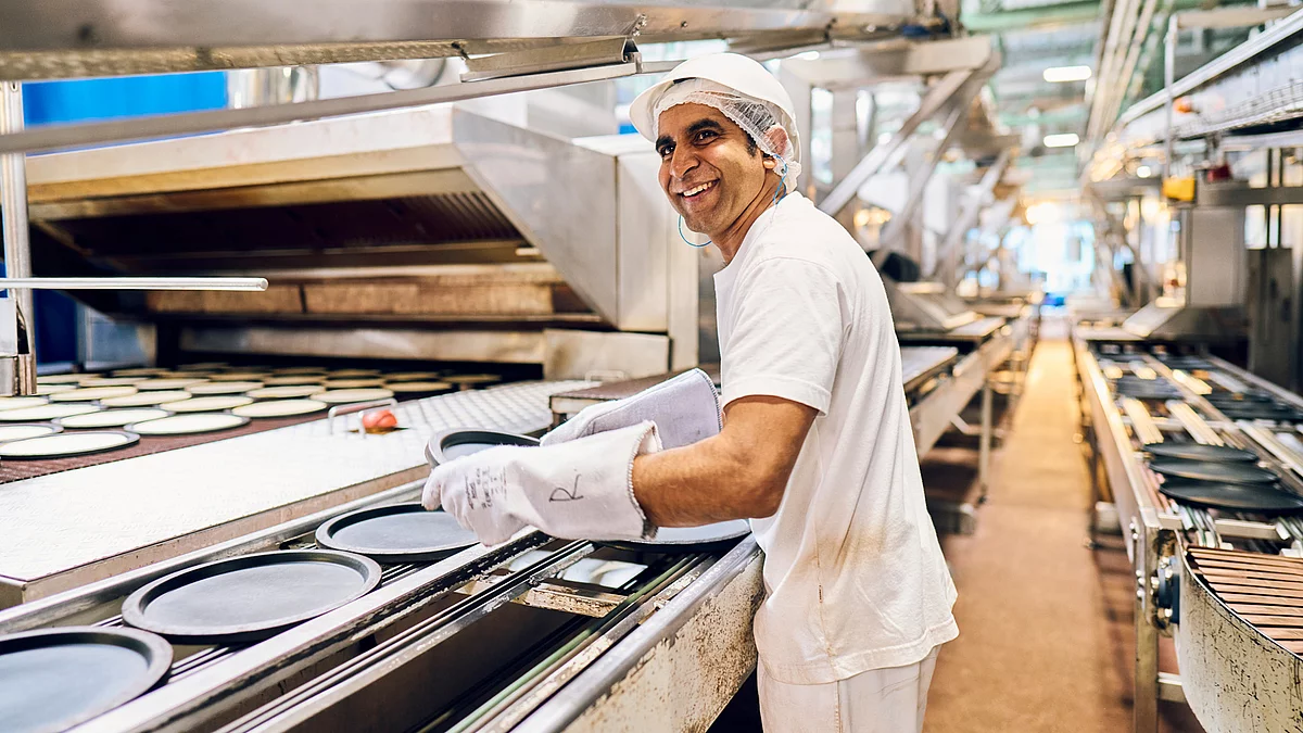 Mitarbeiter in Arbeitskleidung am Produktionsband.