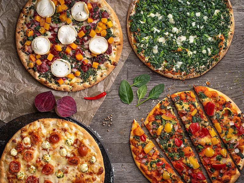 Vier angerichtete Pizzen mit Tomate Mozarella, Paprika, Spinat und Ziegenkäse.