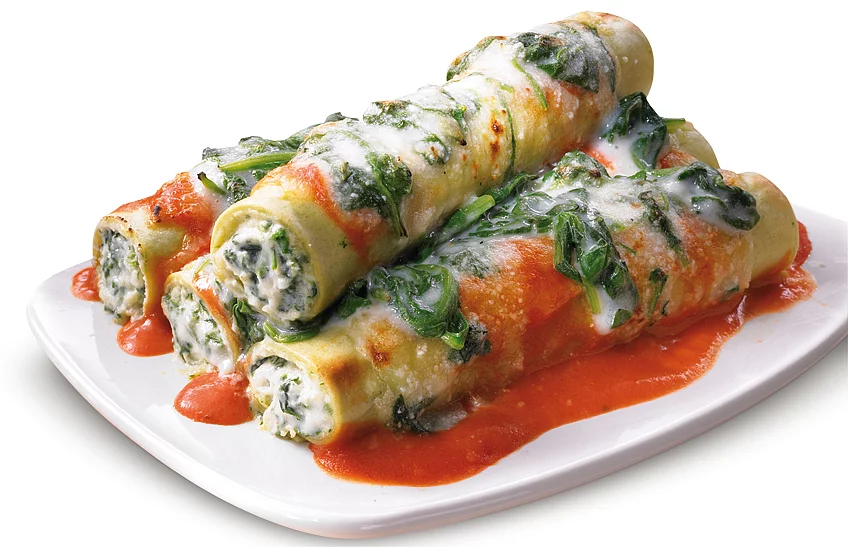Vier Canneloni Pasta mit Spinat und Tomatensoße auf einem Teller angerichtet.