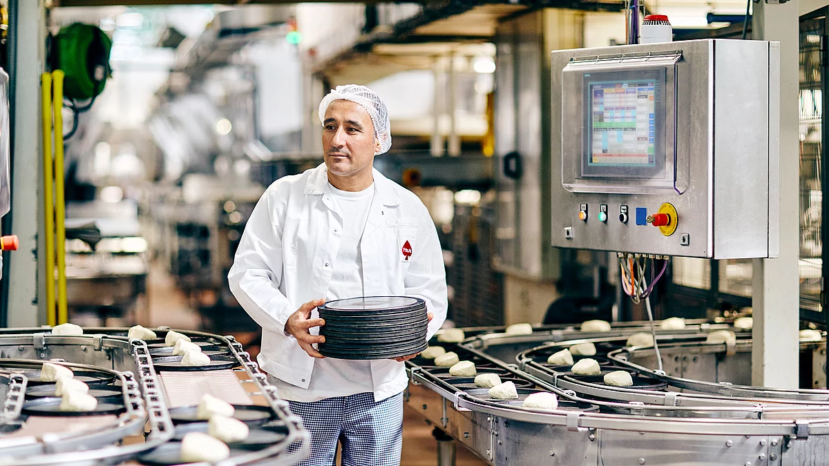 Mitarbeiter in Arbeitskleidung an Produktions Maschine.