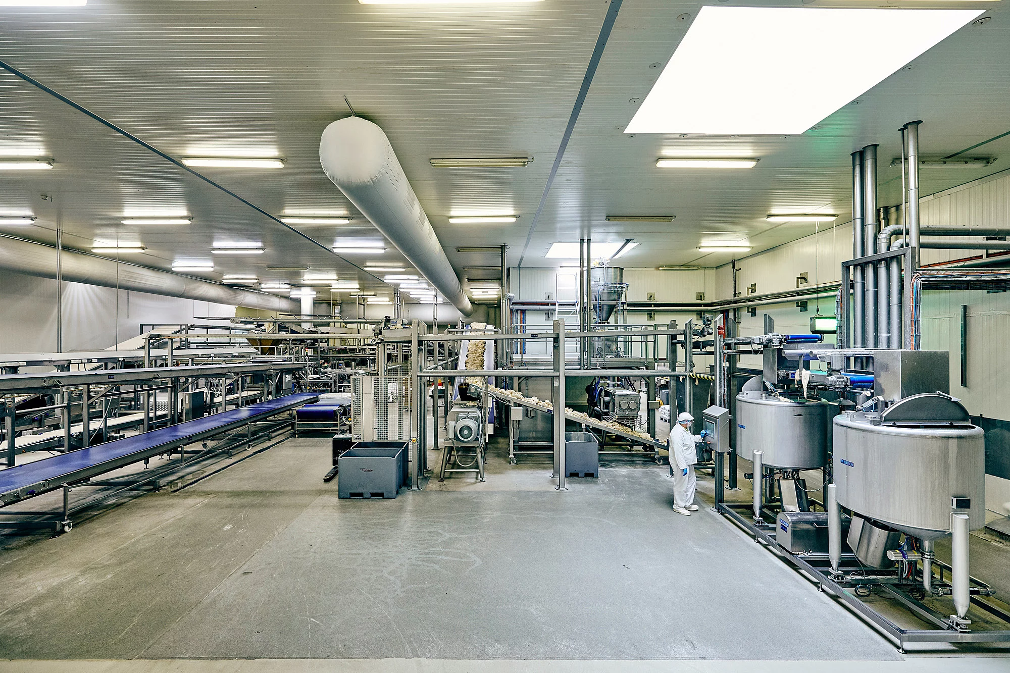 Eine Produktionshalle mit einem Mitarbeitenden an einer Maschine.