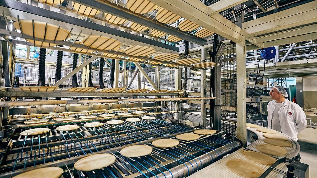 Mitarbeiter in Arbeitskleidung an Produktionsmaschine.